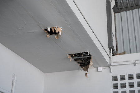 Ceiling panel damaged and crack hole with wire system from rainwater leakageの写真素材
