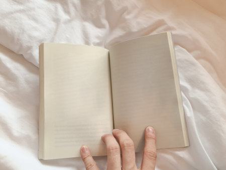 Hand holding blank pages of a book on the bedの写真素材