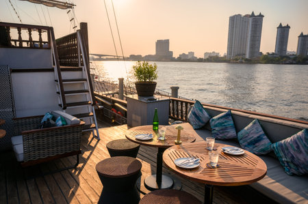 Restaurant on the deck with dining table, sofa, dishware, cutlery on terrace ship in riverside at...