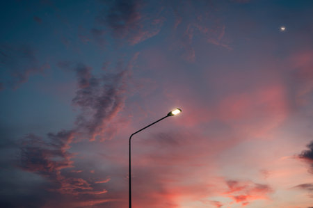 Street light pole with the moon and colorful evening skyの写真素材
