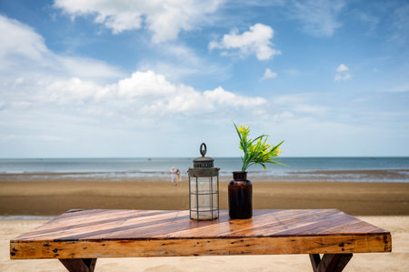 Wooden dining table with lantern and flower in glass on the beach and blue sky on summertimeの写真素材
