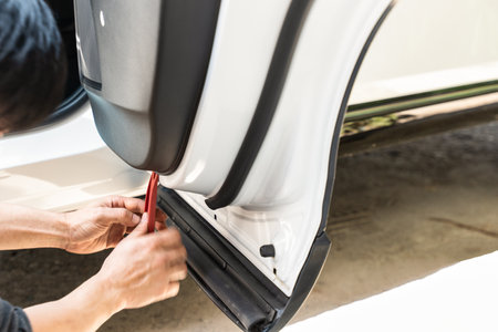 Hand of mechanic using wedge removing and installing a dash cam inside a car at garage workshopの写真素材