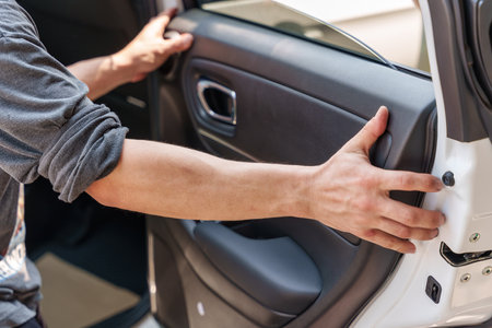 Mechanic man using wedge unpack vehicle door part for checking damage in garageの写真素材