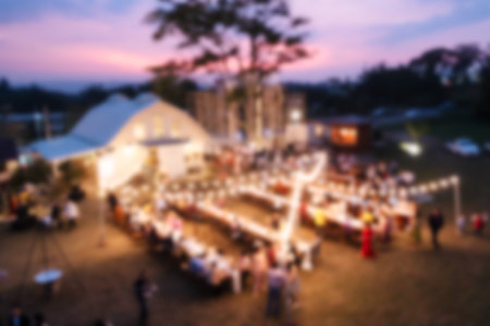 Blurred scene of illuminated catering celebrating with dining table and guests in the sunset