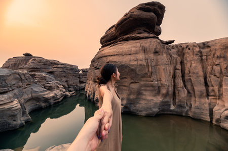 Beautiful asian woman holding hands with couple in rock gorge of grand canyon at eveningの写真素材