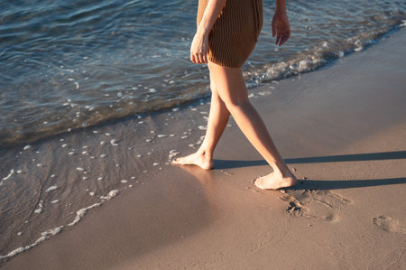 Woman walking barefoot on the beach in the morning at summertimeの写真素材