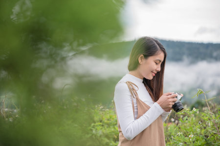 Attractive asian woman taking photo with retro film camera among the nature at countryside in the...