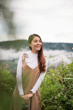Cheerful young asian woman holding retro camera standing in the garden at the morning