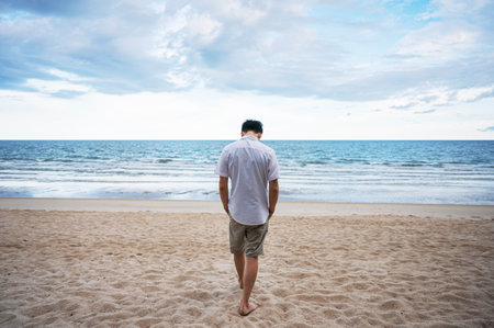 Rear of loneliness man in white shirt walking on the beach in the seaの写真素材
