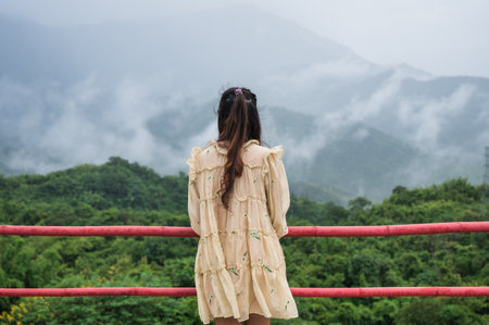 Back of asian woman relaxing and looking with foggy mountain view on rainy season in countrysideの写真素材
