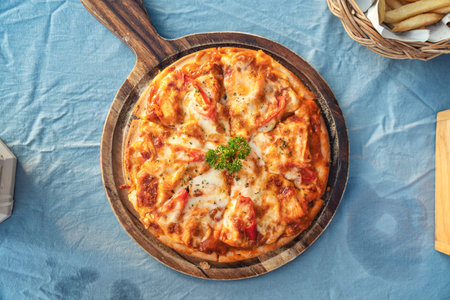 Homemade chicken ham cheese barbeque pizza with chili served on wooden tray in Italian restaurant