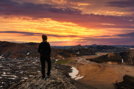 Hiker young female standing on volcanic mountain and sunset sky from Blahnjukur trail on summer at Icelandic Highlandsの写真素材