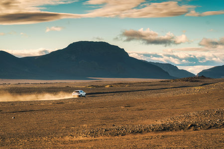 Car driving on desert wilderness among volcanic mountain in summer on the evening at Landmannalaugar, Icelandの写真素材