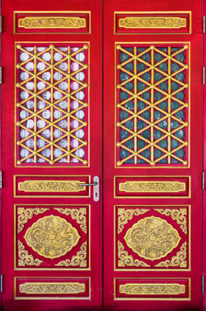 Ancient chinese red wooden door with dragon golden carve gate of chinese templeの写真素材
