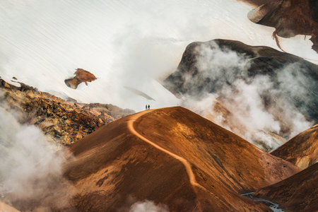 Majestic landscape of Kerlingarfjoll volcanic mountain range with sulfur smoke and tourist hiking on Hveradalir trail in summer at Highlands of Icelandの写真素材