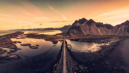 Panorama aerial view of beautiful sunrise over Vestrahorn mountain viking village and road among black sand beach in Stokksnes on summer at Icelandの写真素材