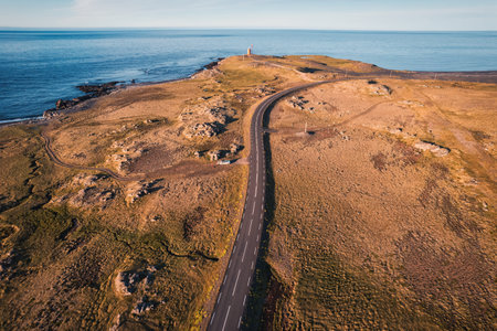 Scenic asphalt road of the ring road with golden field on coastline in summer at Icelandの写真素材