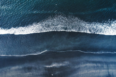 Aerial drone view of moody atlantic ocean wave on black sand beach in summer at Icelandの写真素材