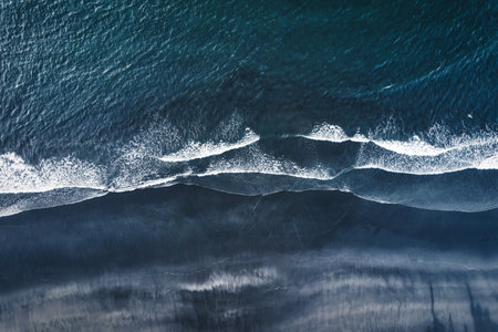 Aerial drone view of moody atlantic ocean wave on black sand beach in summer at Icelandの写真素材