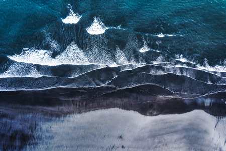 Aerial drone view of moody atlantic ocean wave on black sand beach in summer at Icelandの写真素材