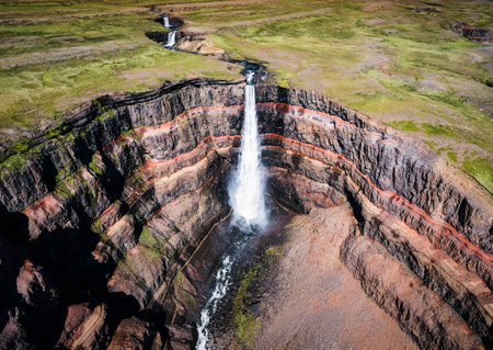 Aerial view of Hengifoss waterfall surrounded by layers of basaltic strata with water flowing in summer at East of Icelandの写真素材