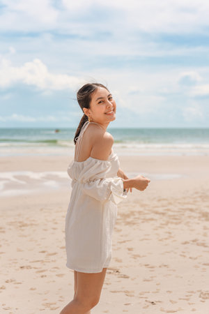 Happy young asian woman in dress enjoying on the beach in summer vacationの写真素材