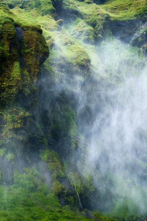 Mystery landscape of waterfall flowing with foggy in lush canyon on summer at Icelandの写真素材