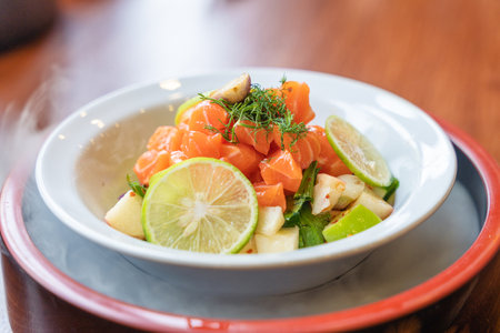 Spicy sliced salmon with fruit salad in white ceramic bowl. Fusion food appetizer dishの写真素材