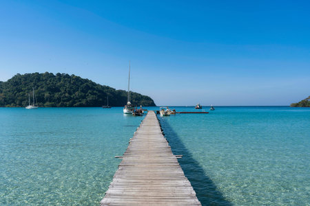 Beautiful scenery of wooden pier in the tropical sea and sightseeing boat anchored in sunny day on summer at Koh Kood Islandの写真素材