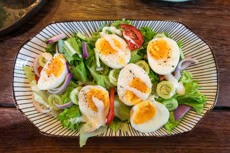Stir fried mixed salad with boiled egg and sauce, Healthy food in ceramid plate on wooden tableの写真素材