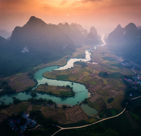 Aerial view of beautiful sunrise over mountain range with foggy on rural village and river flows through in Phong Nam Valley, Cao Bang, Northern of Vietnamの写真素材