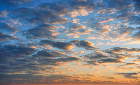 Beautiful colorful fluffy clouds and warm sunrise shines on blue skyの写真素材