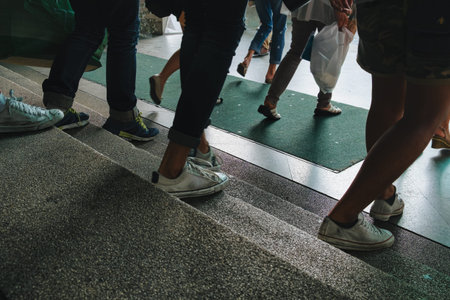 Legs and feet of pedestrians walking down textured steps indoor building at city environment