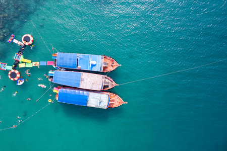 Above of traditional ferry anchored and tourist snorkeling and enjoying with coral reef in tropical...