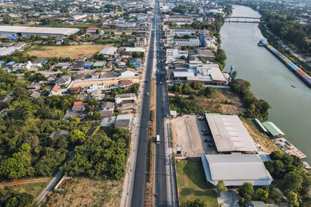 Aerial view of car driving on highway road with local village and commercial building in suburban at...