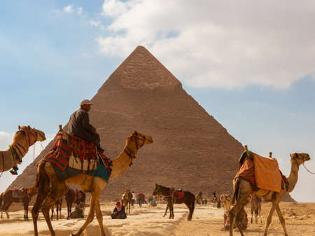 Giza, Egypt - January 29, 2020 - Tourist bustle with camels and people in front of a pyramidのeditorial素材