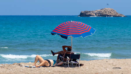 Heraklion, Greece - August 20, 2021 - Two vacationers relax on a beach near Heraklion, Creteのeditorial素材