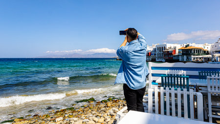 Mykonos, Greece - May 3, 2022 - A tourist photographs the Greek town on the island of the same name, Mykonosのeditorial素材