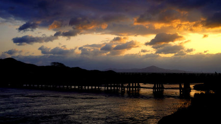 Sunset over the river and the silhouette of the bridge in the evening