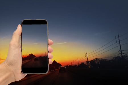 Hand holding smartphone on car driving on road at nightの写真素材