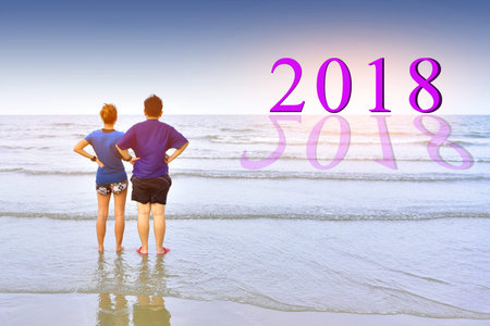 People standing on beach at sea under blue sky and look at year 2018