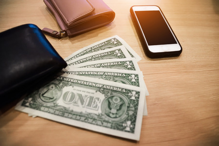 Smart phone and dollar for pay or buy product put on wooden table,Money for everyday shopping and Investment for saving conceptの写真素材