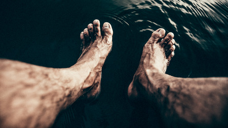 Men sit on the boat and take their feet soaked in water.の写真素材