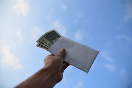Hand holding dollar money against blue sky on background,Business Investment and saving conceptの写真素材