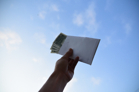 Hand holding dollar money against blue sky on background,Business Investment and saving conceptの写真素材