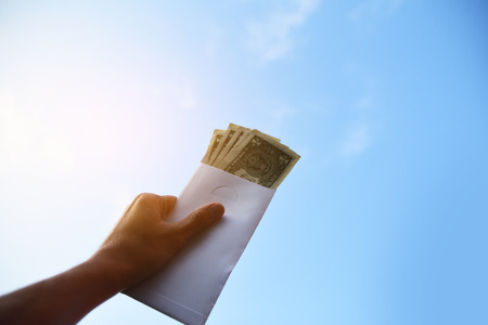 Hand holding dollar money against blue sky on background,Business Investment and saving conceptの写真素材
