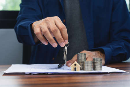 Closeup salesman holding home key to business sale estate rent conceptの写真素材