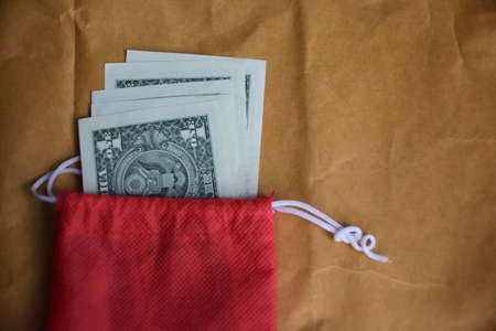 US dollar money in red bag on brown backgroundの写真素材