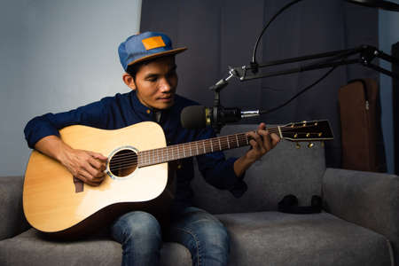 Man playing guitar in home studio live streaming onlineの写真素材
