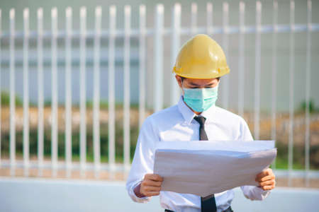 Engineer hold paper work or blueprint and survey on site constructionの写真素材